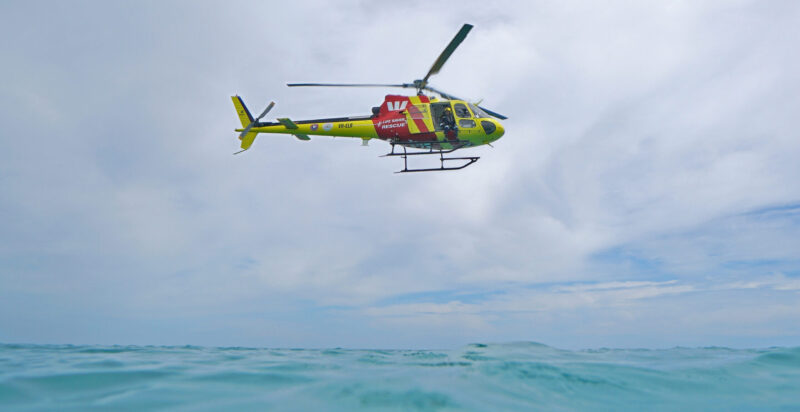 Westpac Lifesaver Rescue Helicopter hovers over water.